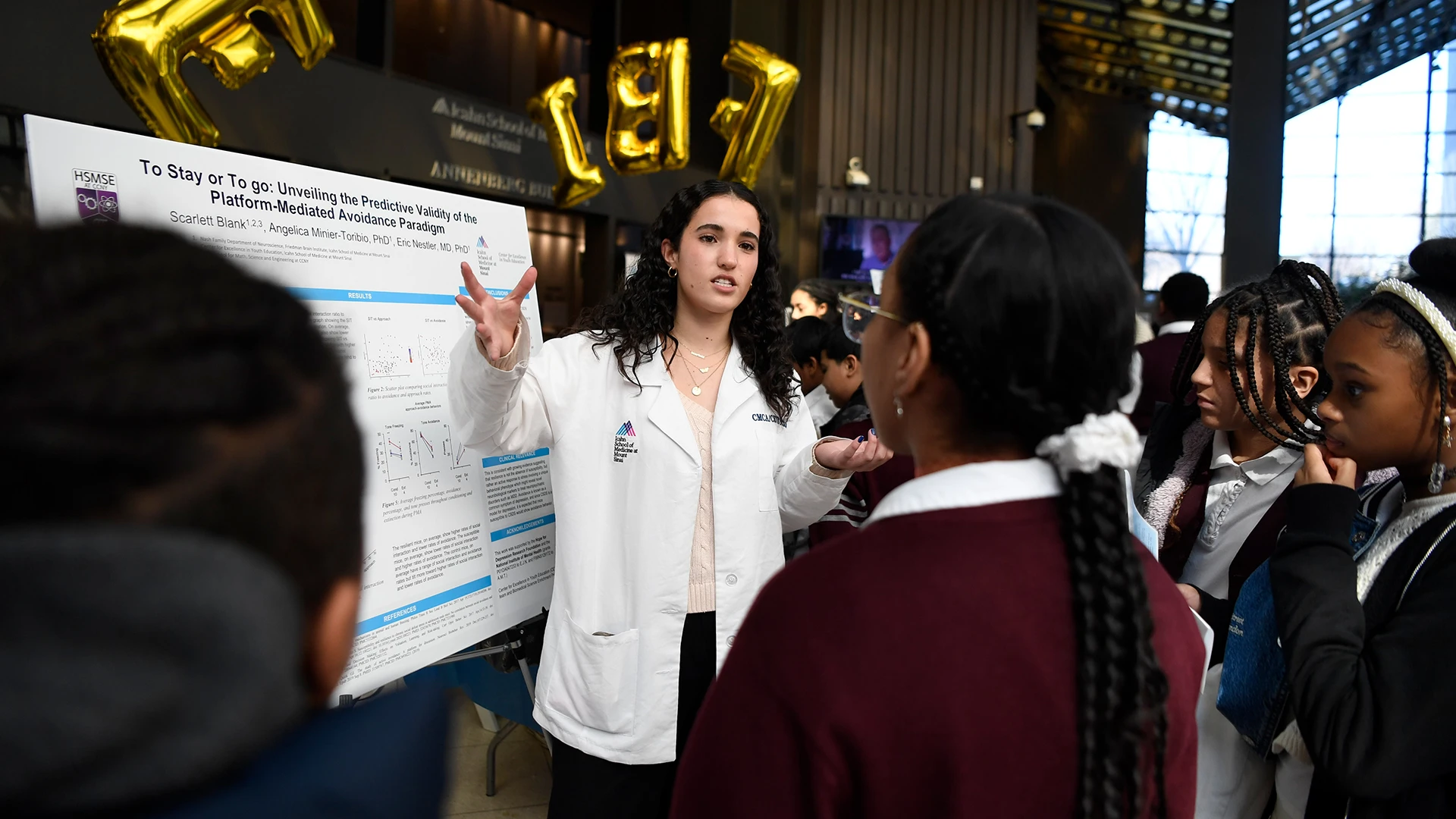 High school junior Scarlett Blank explains her research to curious students.