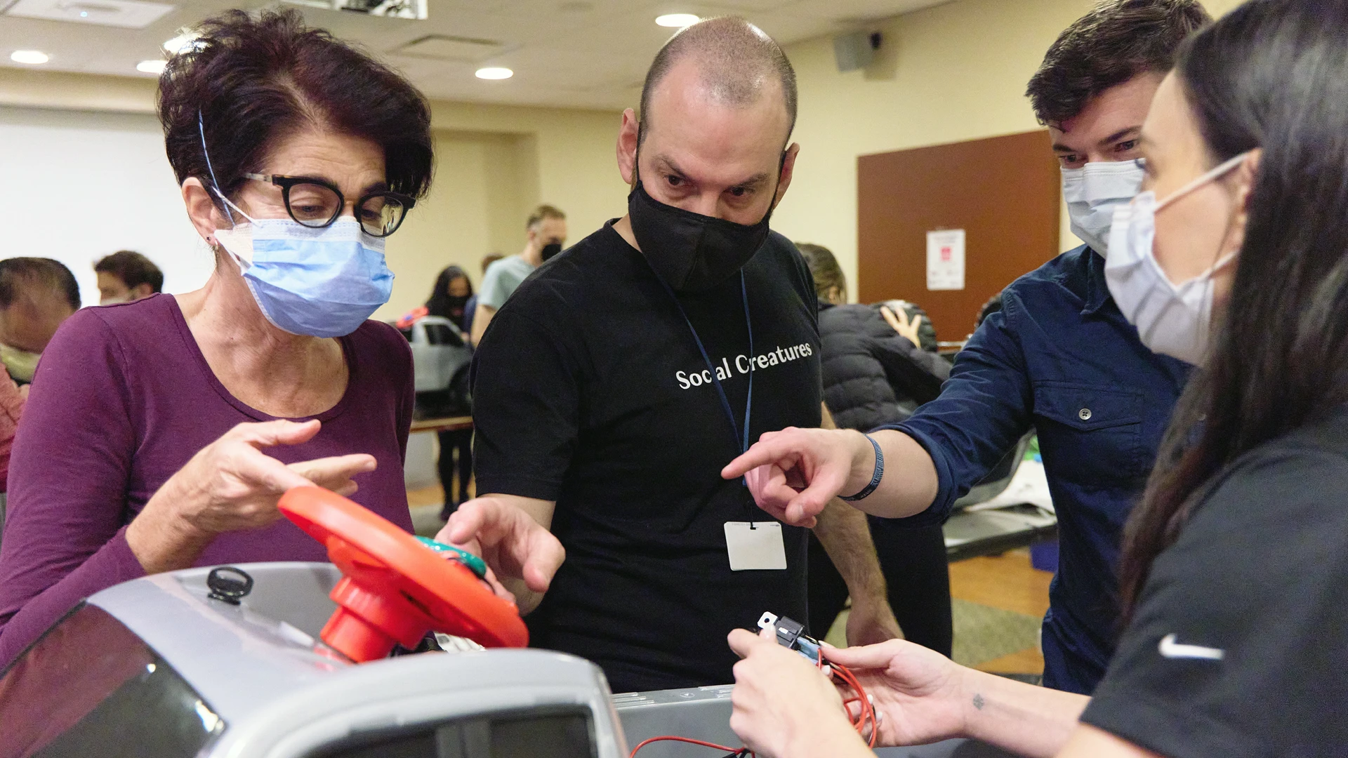 David Putrino, PhD (second from left), and Jimmy McKay, DPT, PT (second from right), examining a custom steering wheel, which has controls for accelerating the car, instead of using a foot pedal.