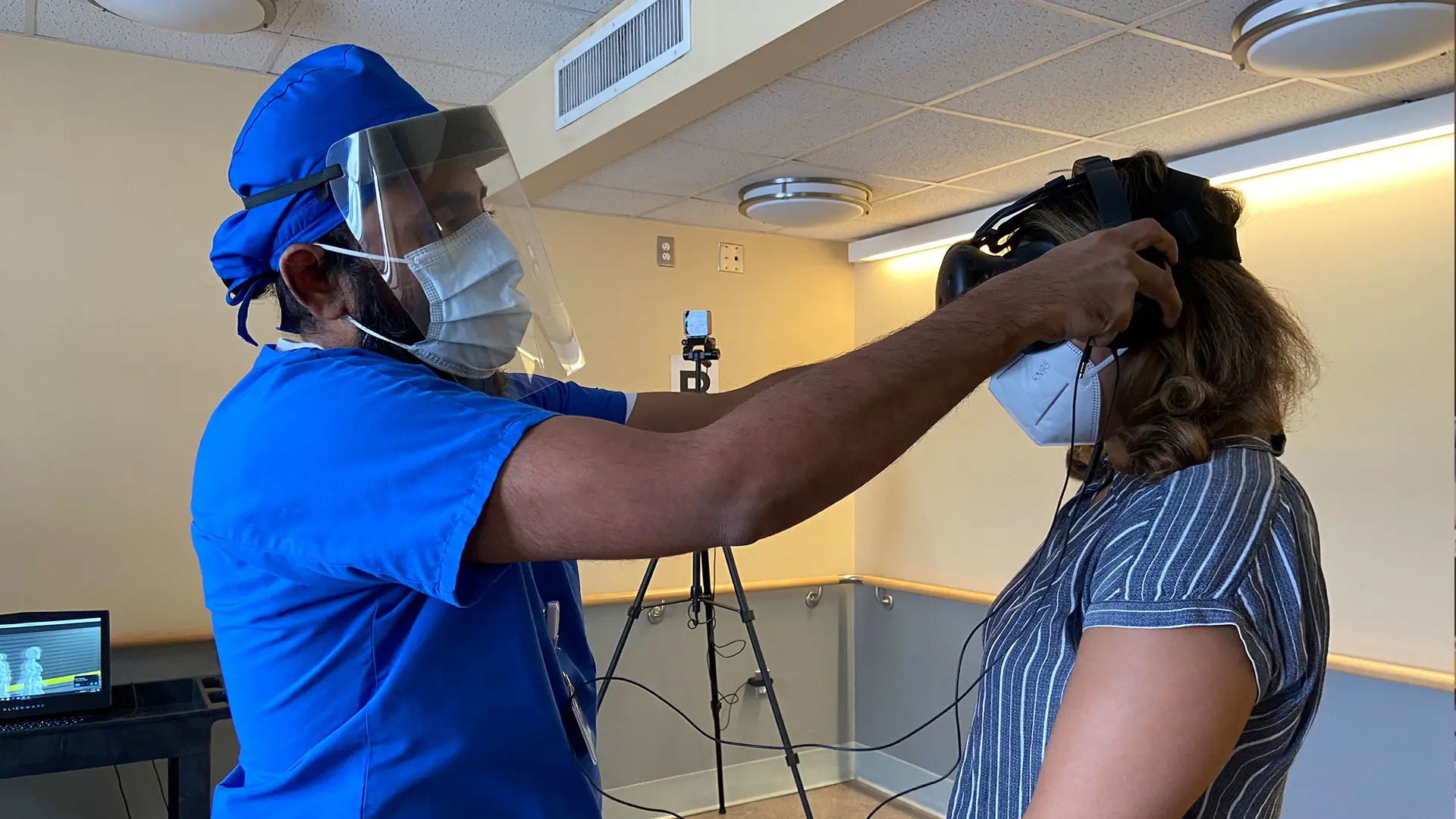 A patient (right) is fitted with a VR headset. 