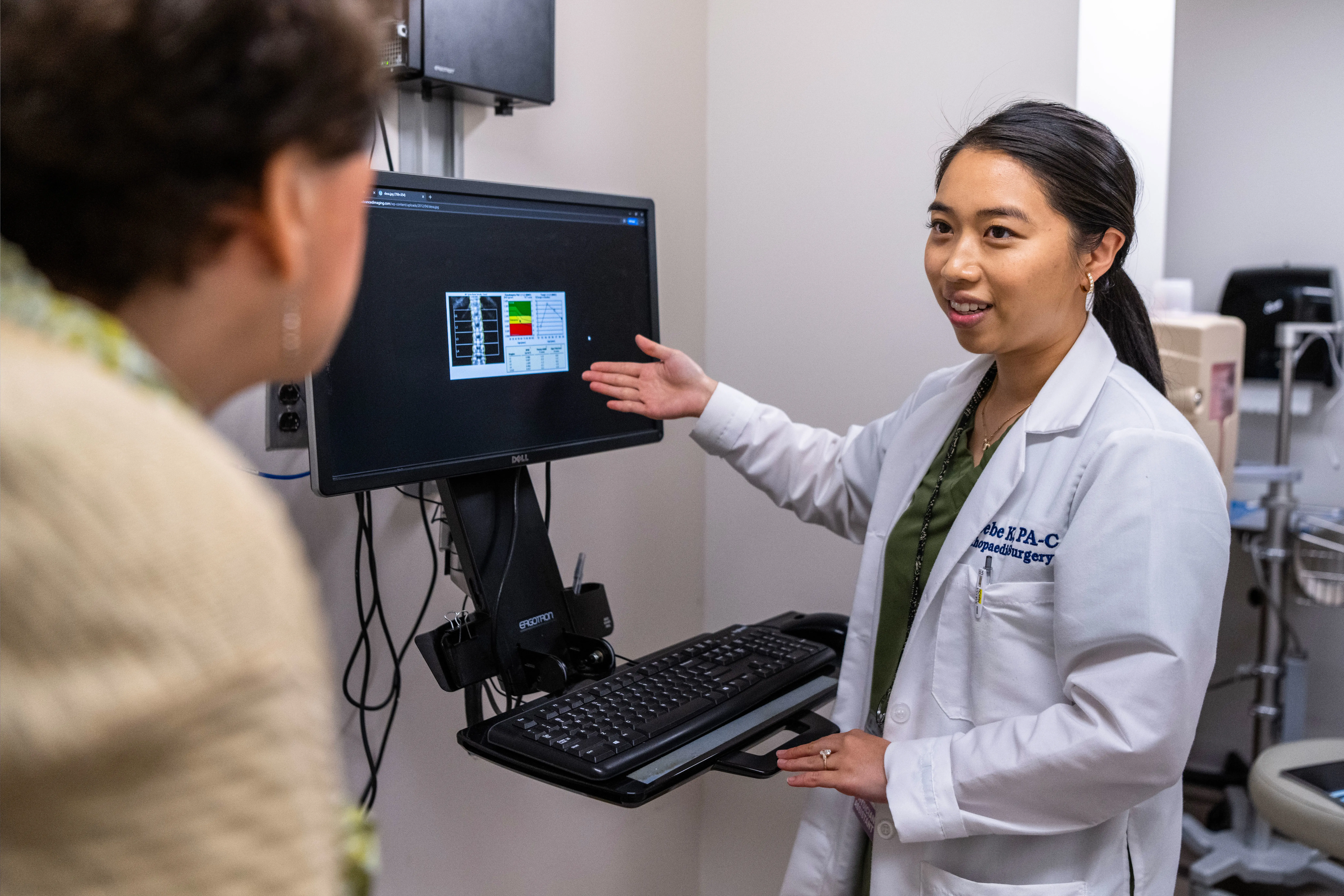 Ms. Ke reviews a bone density scan with a patient.