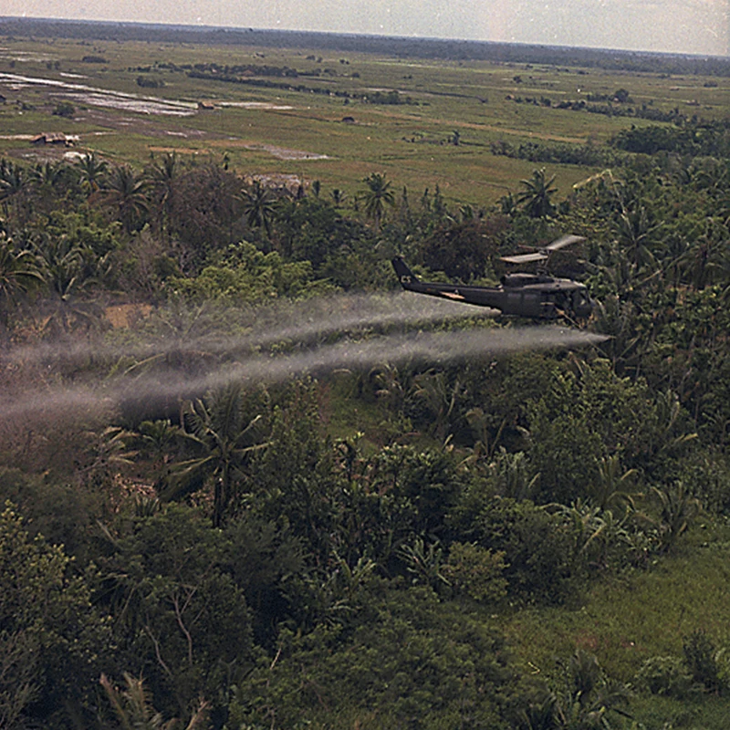 In July 1969, a UH-1D helicopter from the 336th Aviation Company of the U.S. Army sprays a defoliation agent on a dense jungle area in the Mekong River Delta in southern Vietnam. [Image via archives.gov]
