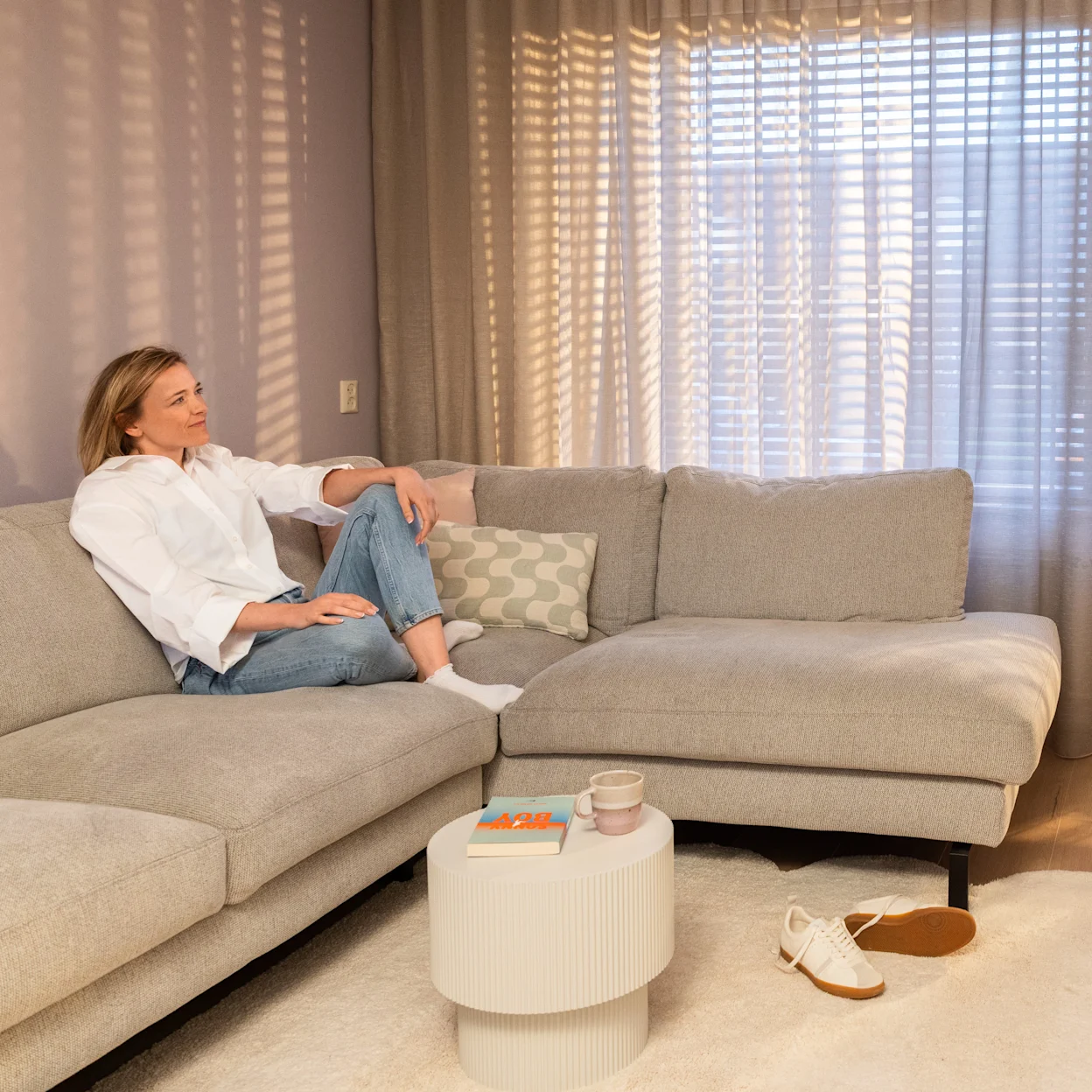 Beige hoekbank met raamdecoratie