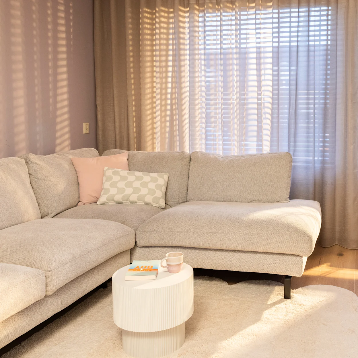 Beige hoekbank met raamdecoratie