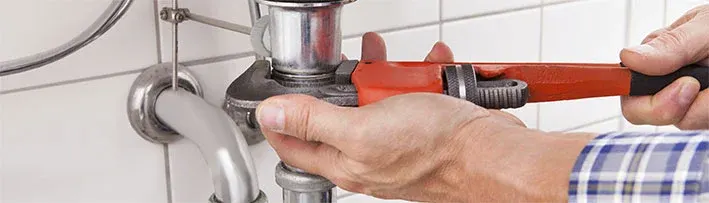 plumber tightening a sink pipe