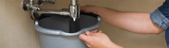 bucket under a sink catching water from the P-trap