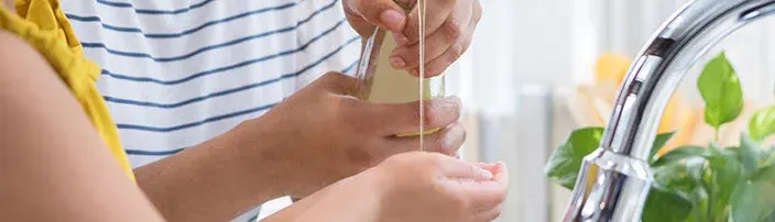 two people washing hands over kitchen sink