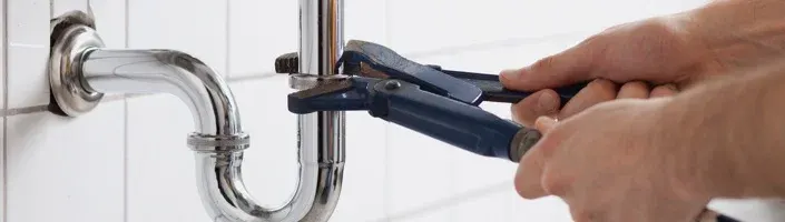 plumber unscrewing pipe with a wrench