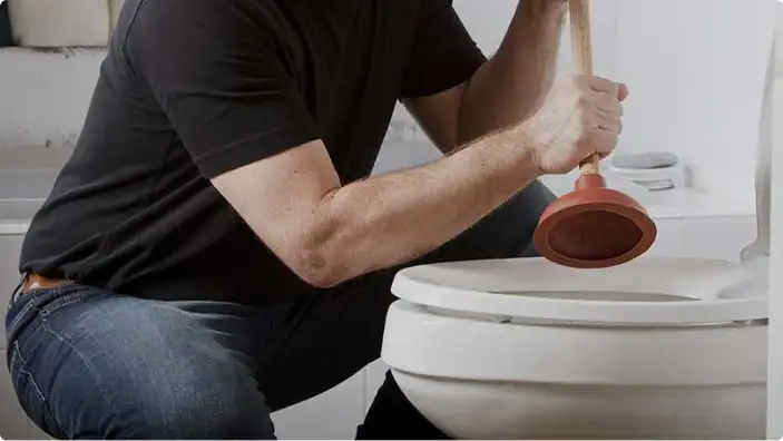 A person using a plunger to unclog a toilet