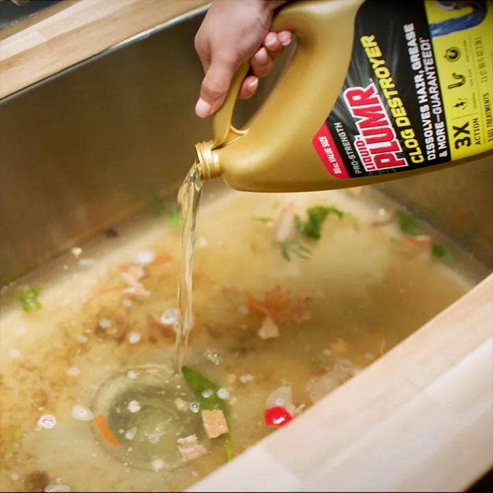 Liquidplumr bottle pouring into dirty clogged kitchen stainless steel sink