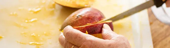 person cutting a mango with a knife