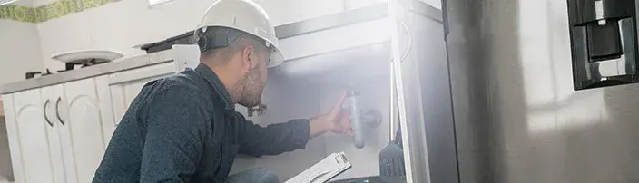 plumber inspecting kitchen sink pipes