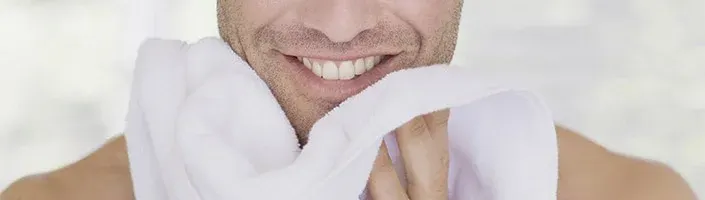 smiling man wiping face with a towel