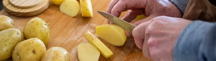 person slicing potatoes on a cutting board