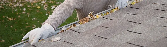 person cleaning out roof gutters