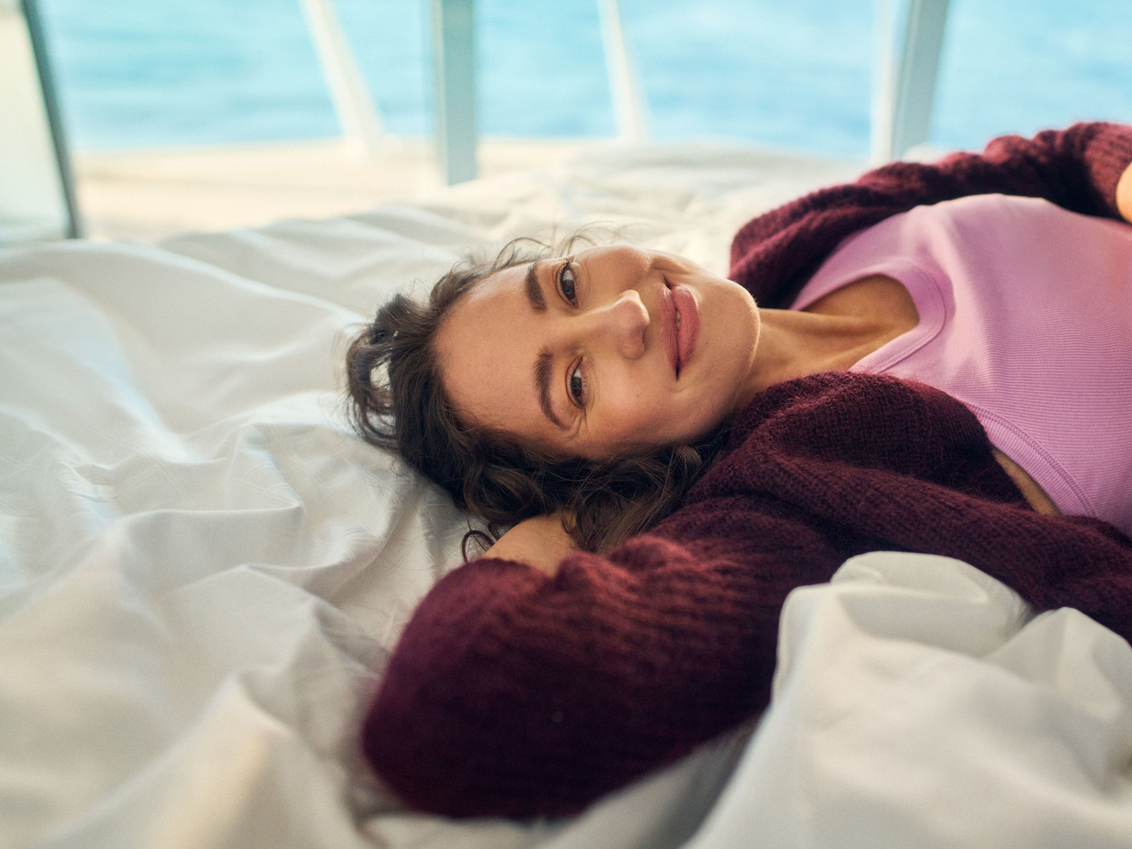 Frau liegt im Bett in Kabine und lächelt in die Kamera