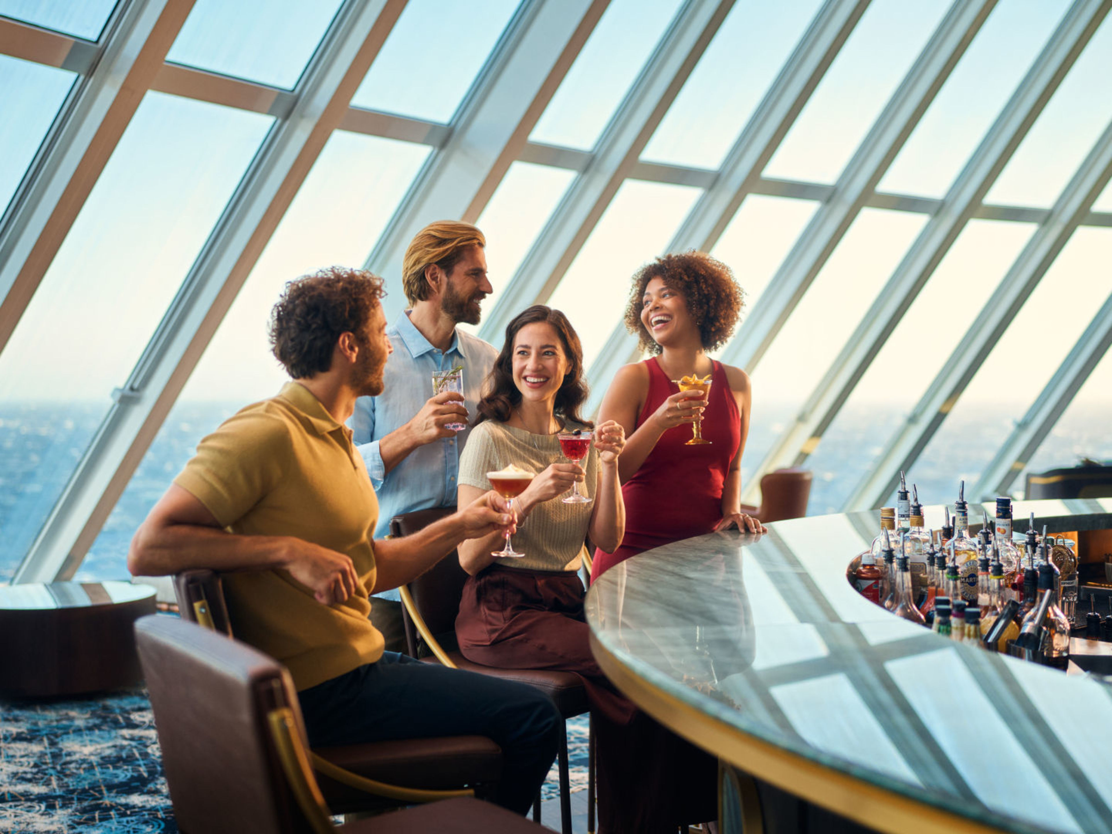 Genießen Sie ihre Getränke und die Gemeinschaft z.B. in der Captains Bar Zwei Paare genießen ihre Getränke und die Gemeinschaft in einer Bar mit tollem Ausblick auf das Meer.