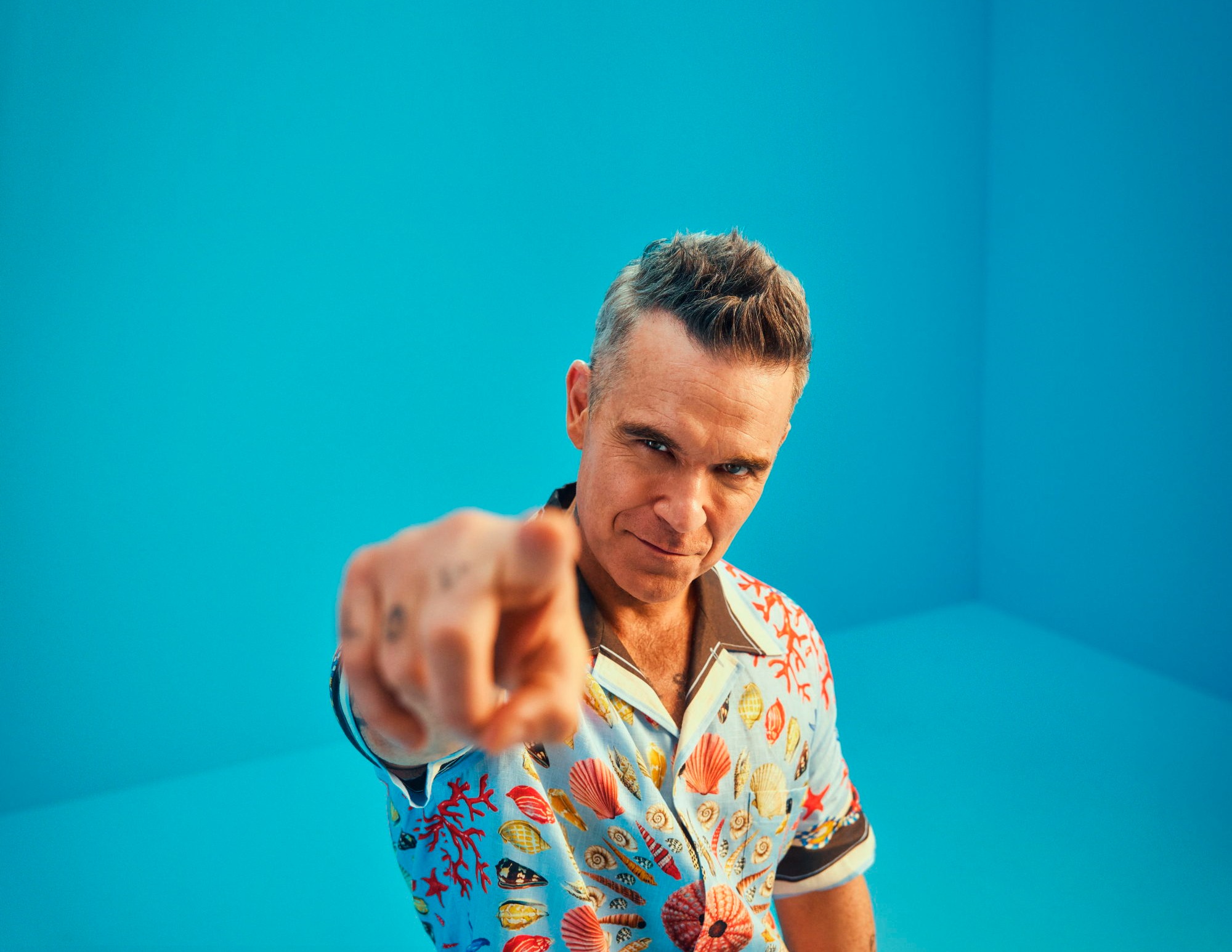 Robbie Williams zeigt mit Finger in Richtung Kamera