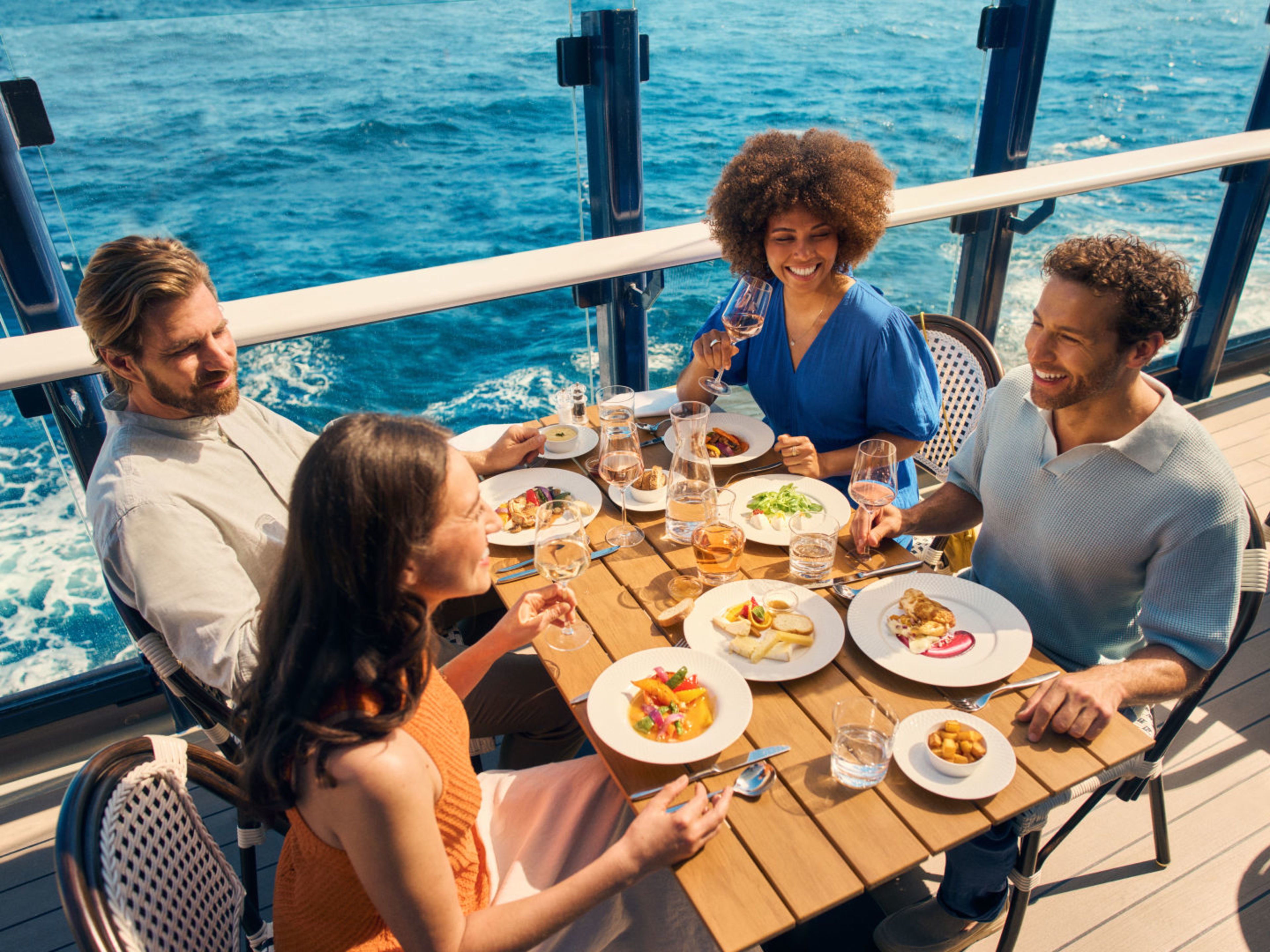 Freundesgruppe genießt ihr Essen im Außenbereich des Sur Mer Bistrots Freundesgruppe genießt ihr Essen im Außenbereich des Sur Mer Bistrots