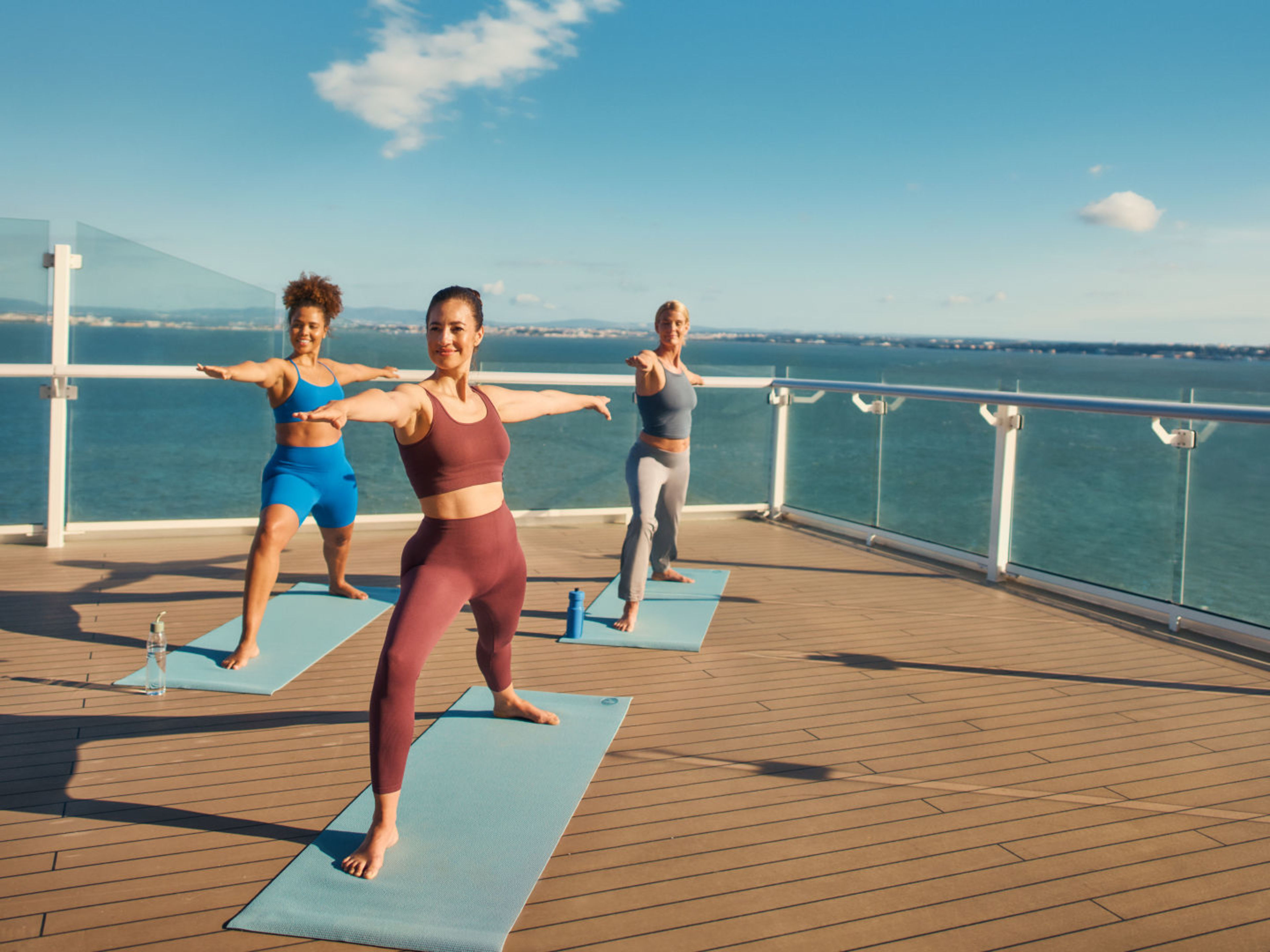 Drei Freundinnen machen gemeinsam Yoga in der Sonne an Deck Vielfältiges Sport- und Fitnessprogramm: z. B. Yoga in der Sonne an Deck
