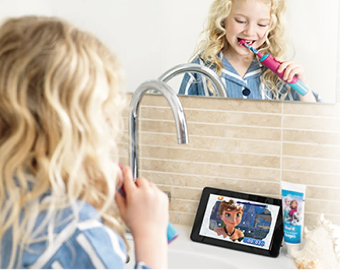 Girl brushing her teeth with Oral-B's Frozen electric toothbrush and using the Disney Magic Timer app
