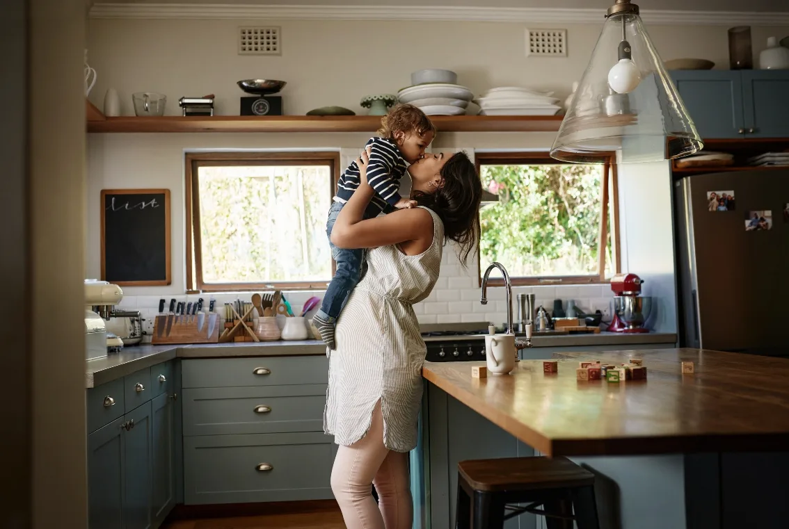 Happy mom holding up child in kitchen