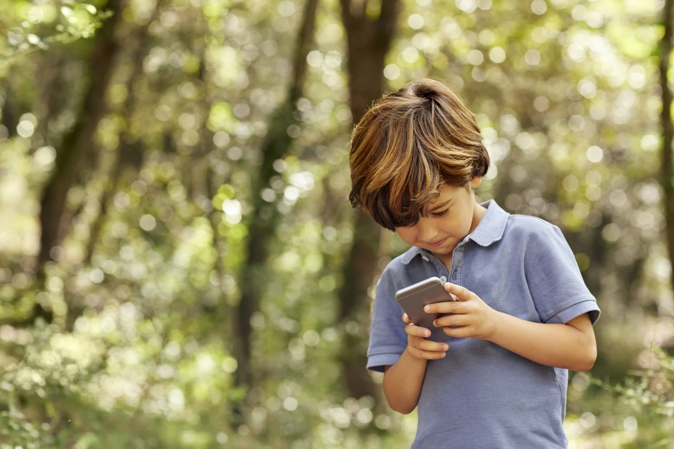 little boy on phone in the woods