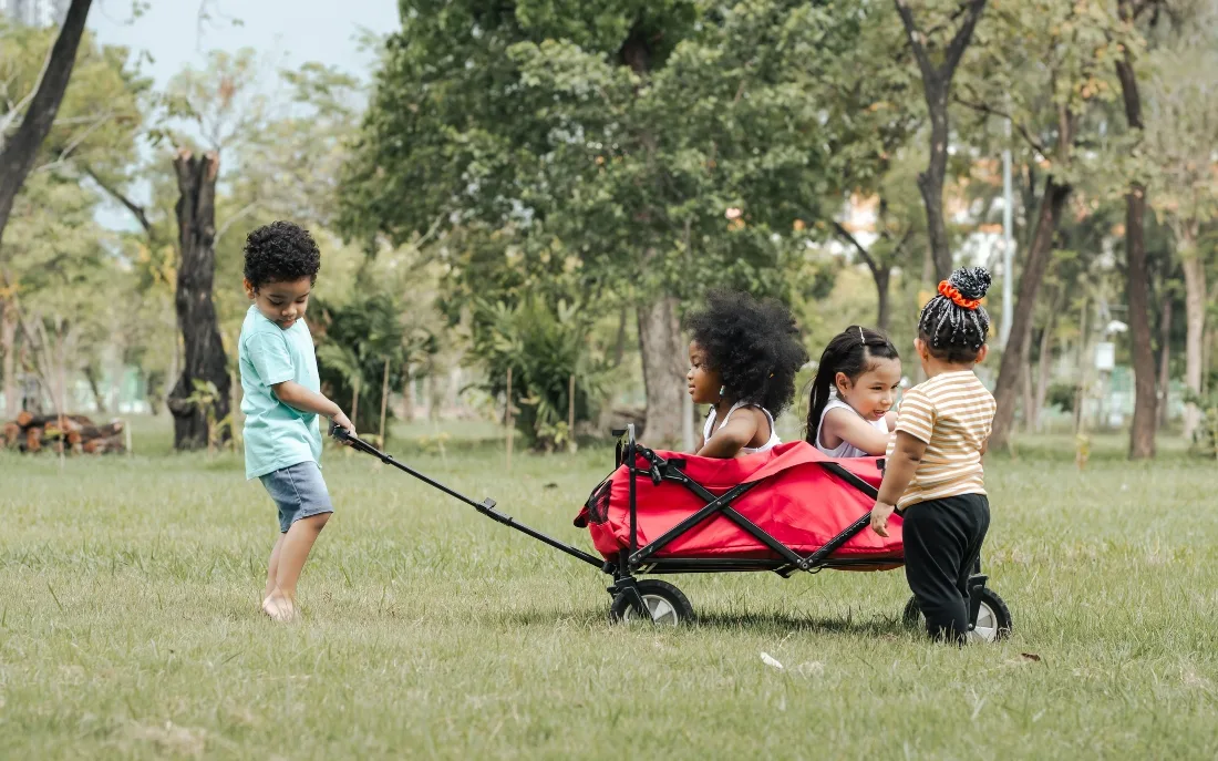 Little boy pulls wagons with other children in it