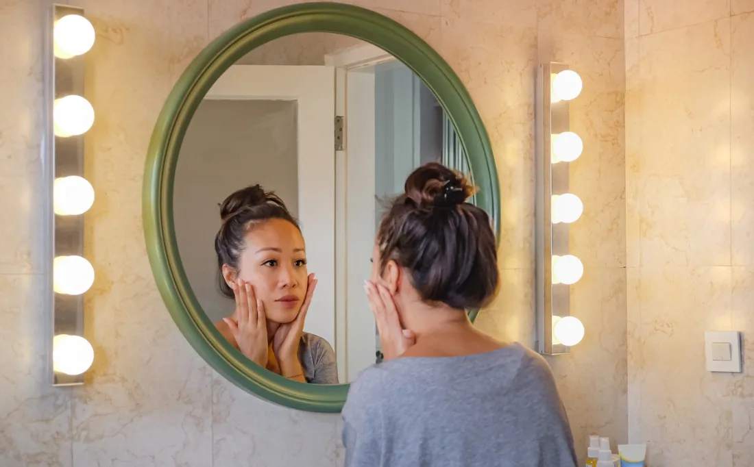 worried-east-asian-woman-checking-her-face-skin-in-the-mirror-picture-id1270369920