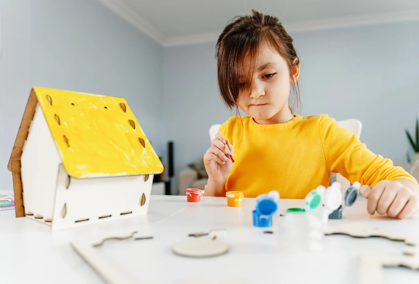 little girl painting a birdhouse