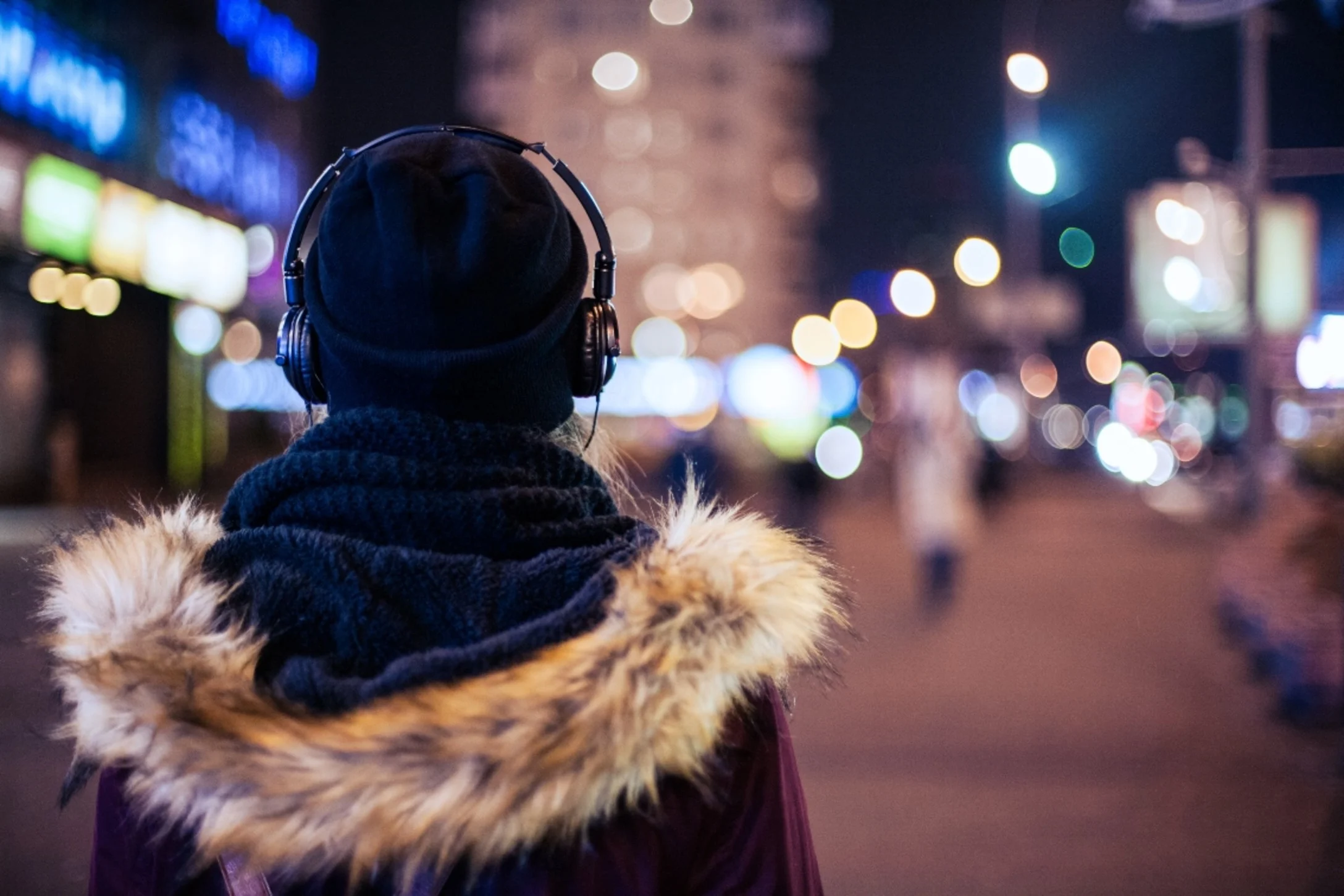 Woman walking outside on a street with headphones on