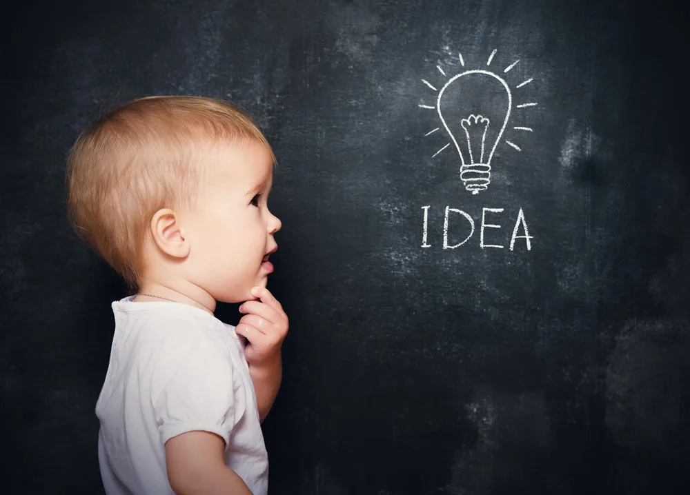 baby child at the blackboard with chalk drawn light bulb symbol ideas