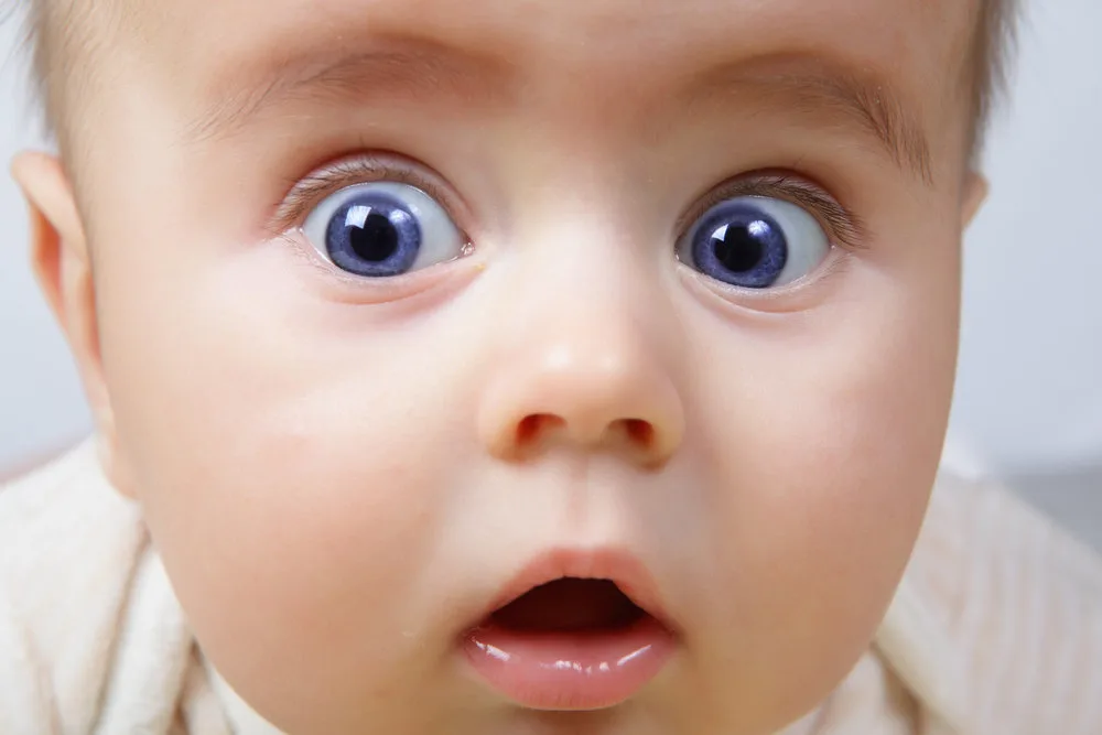 head shoot of cute baby with blue eyes and surprise look