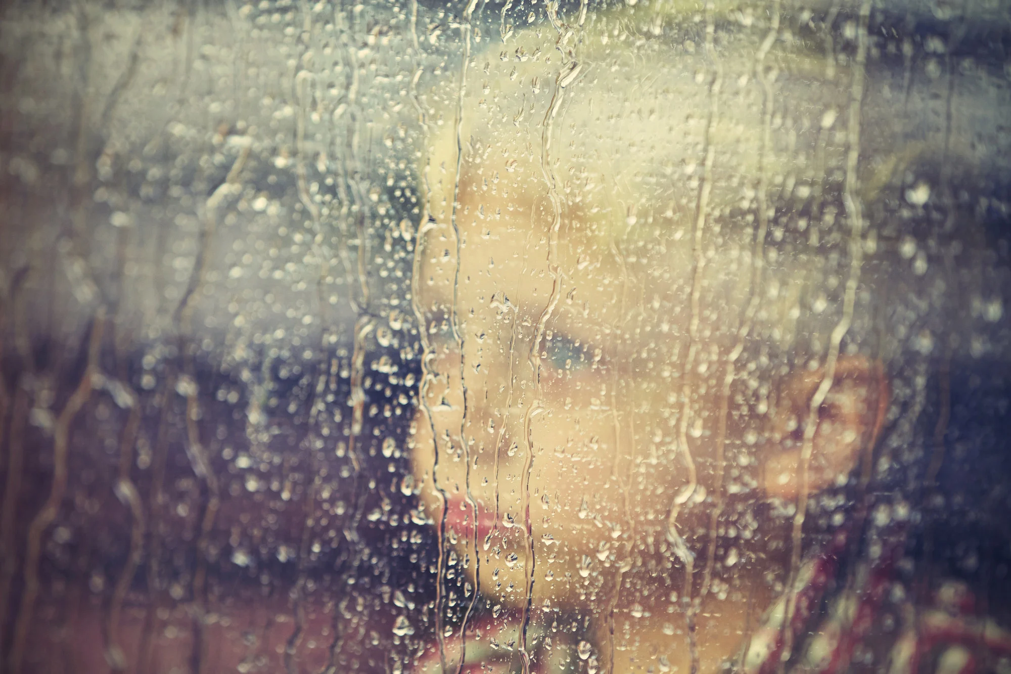 kid looking out window on rainy day