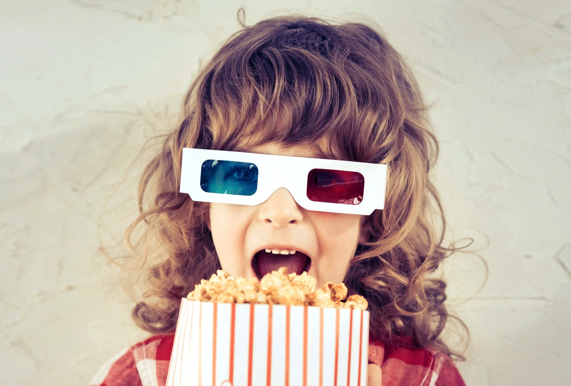 Cute girl watching movie with 3D glasses and popcorn