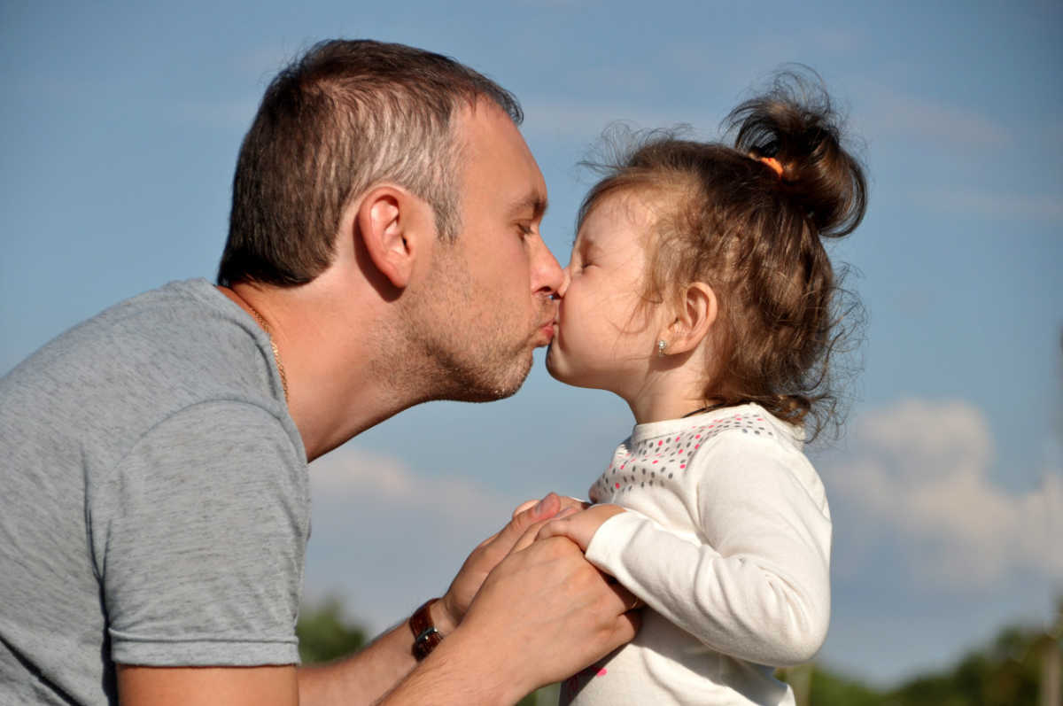 dad kissing daughter on lips.