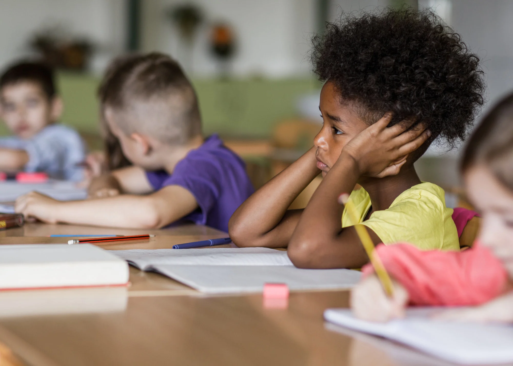 Child sits in class looking sad