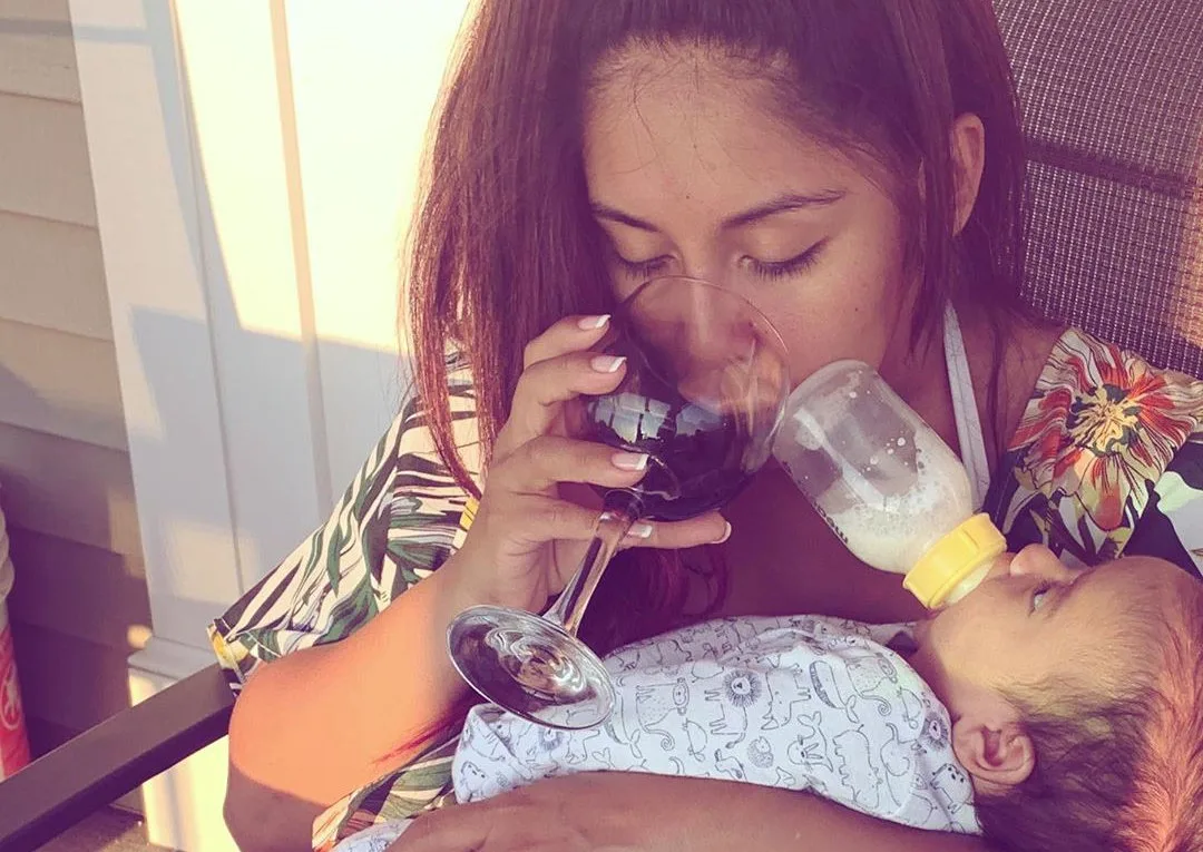 Snooki drinking wine while feeding her baby son