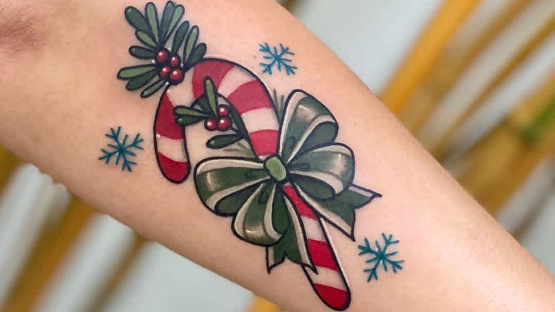 Amazing Christmas Tattoos. Here is a candy cane tattoo with the mistle toe and snowflakes.