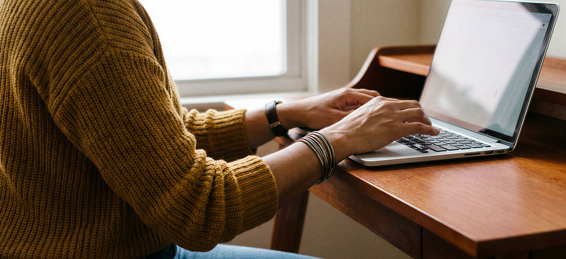Small business owner sitting at a desk with a laptop and paperwork, opening a U.S. business bank account online.