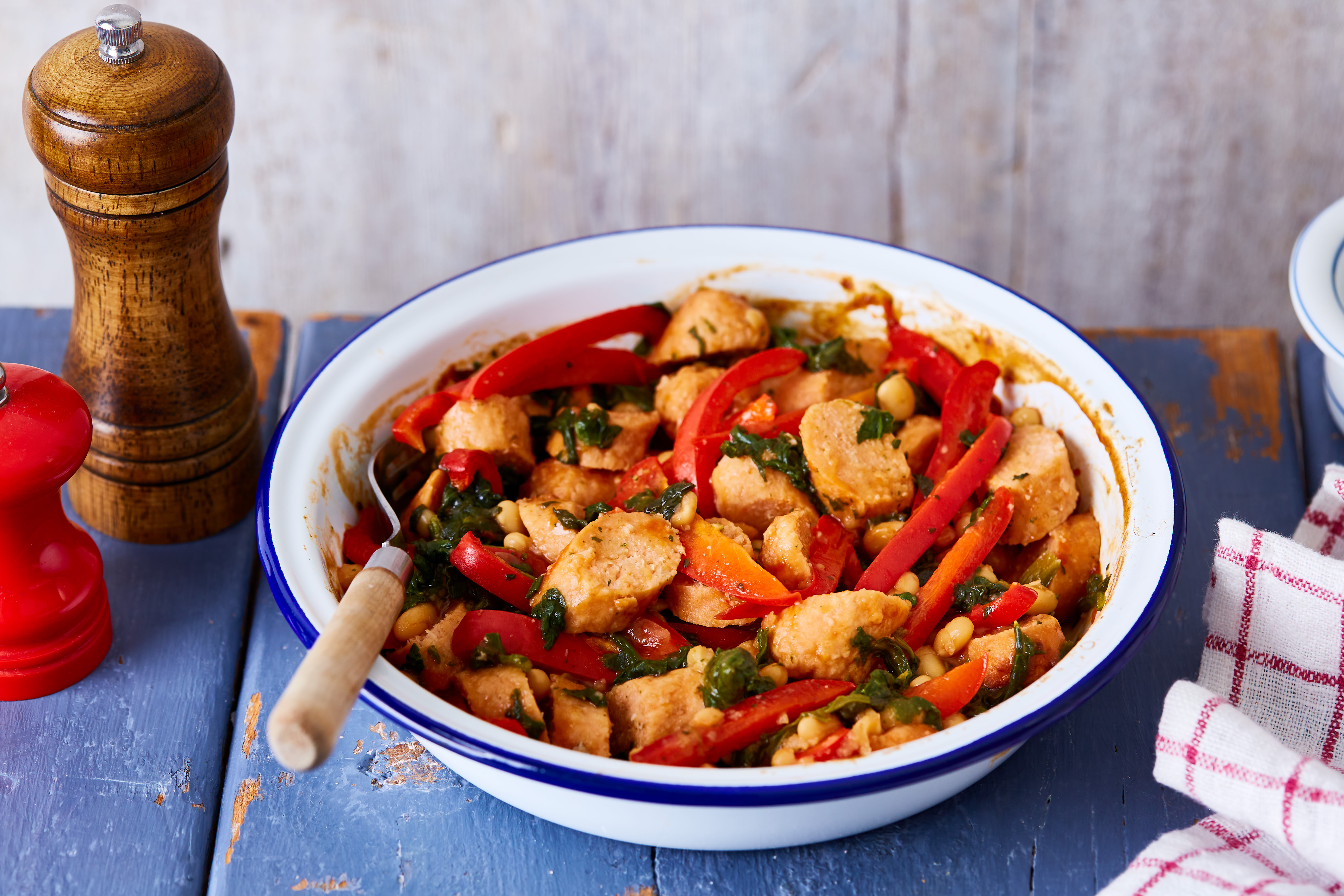 Vegan sausage and pepper breakfast traybake served in a ceramic bowl on a wooden table.