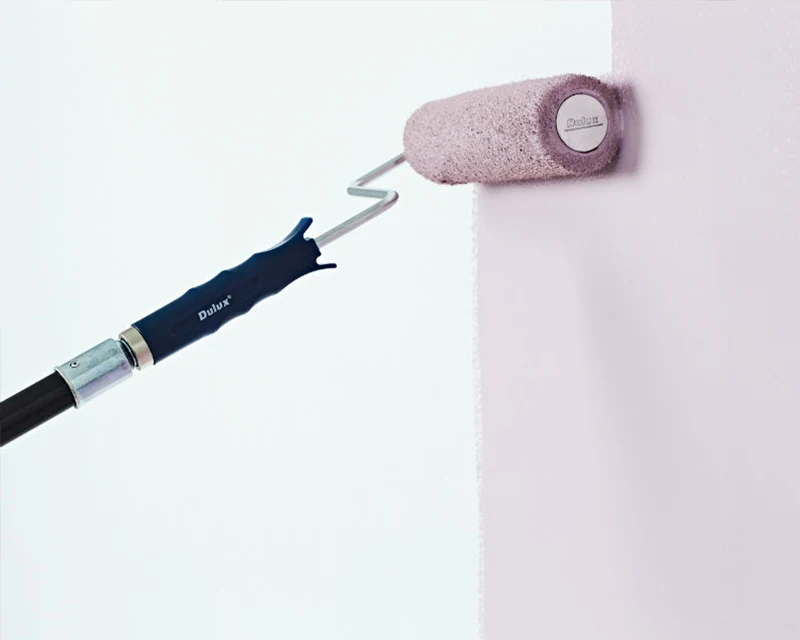 a paint roller rolling pink paint onto a white wall