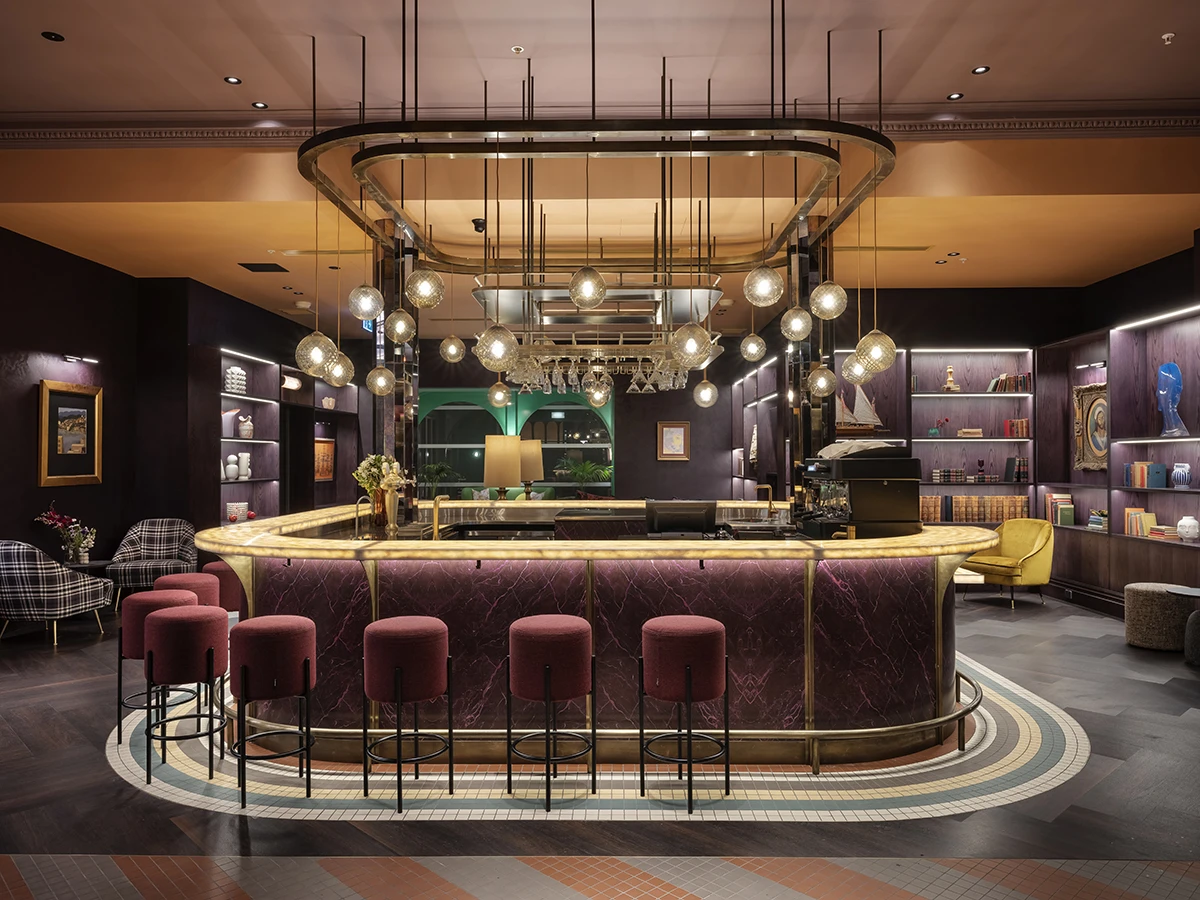 Classy purple bar centrally located in room with with velvet stools, round pendant lights.
