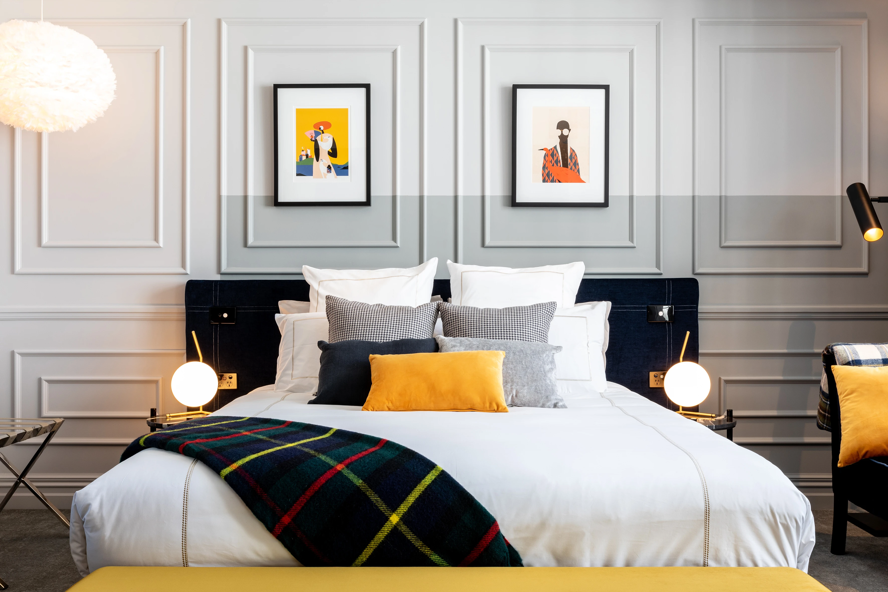 Hotel room with grey walls, artwork and bed with pillows and cushions