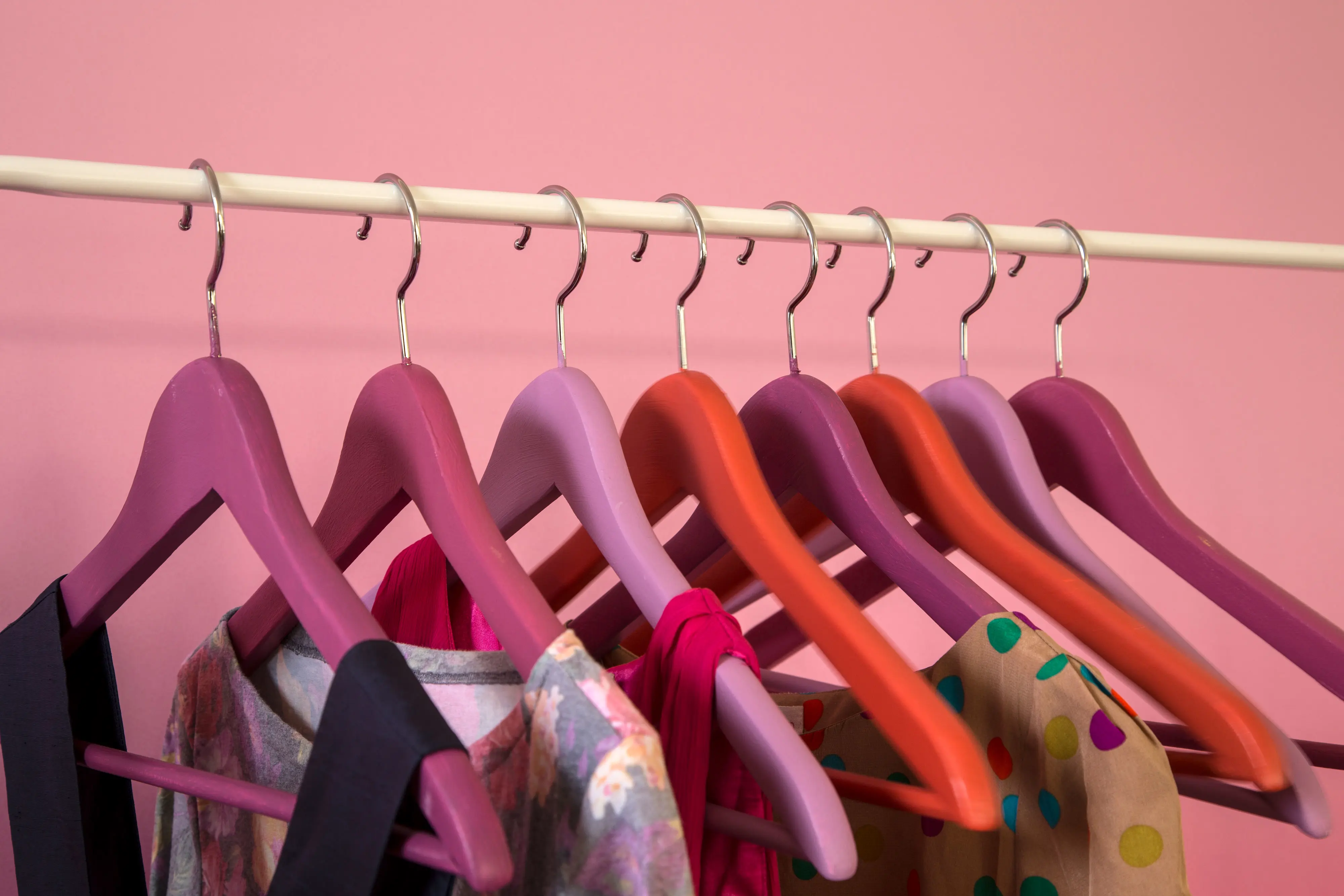 Clothes on wooden coat hangers painted in different shades of pink