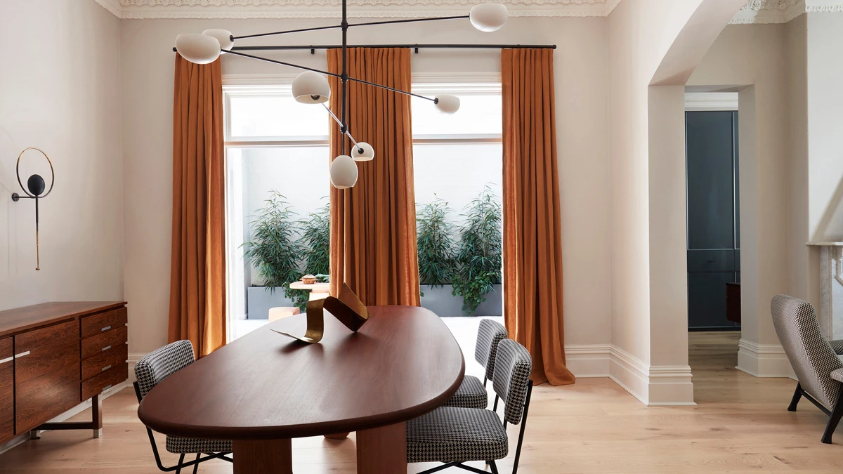 Dining area in home with decorative lighting, buffet against wall looking out windows.