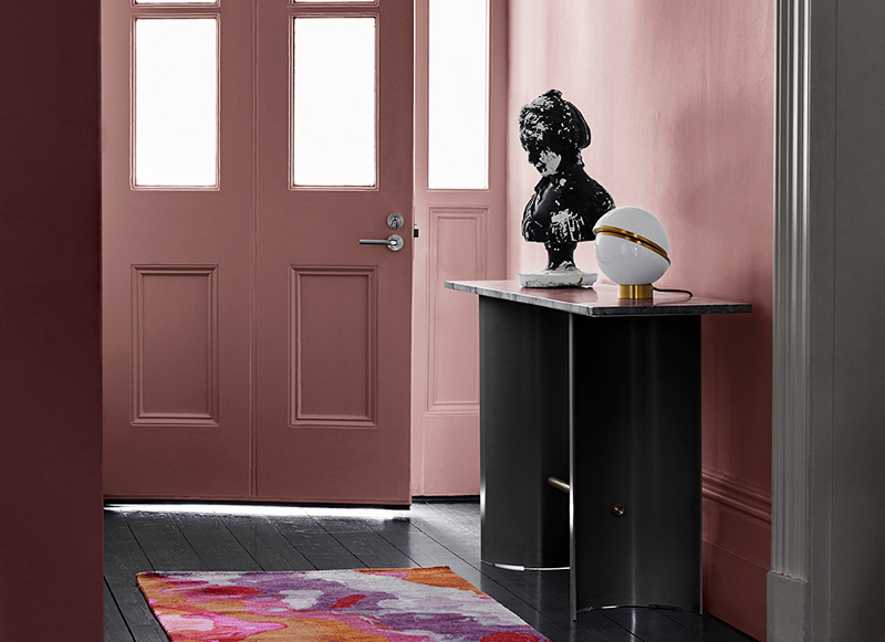 Traditional hallway in pink and maroon with black hardwood floors, black hall table and multicoloured runner