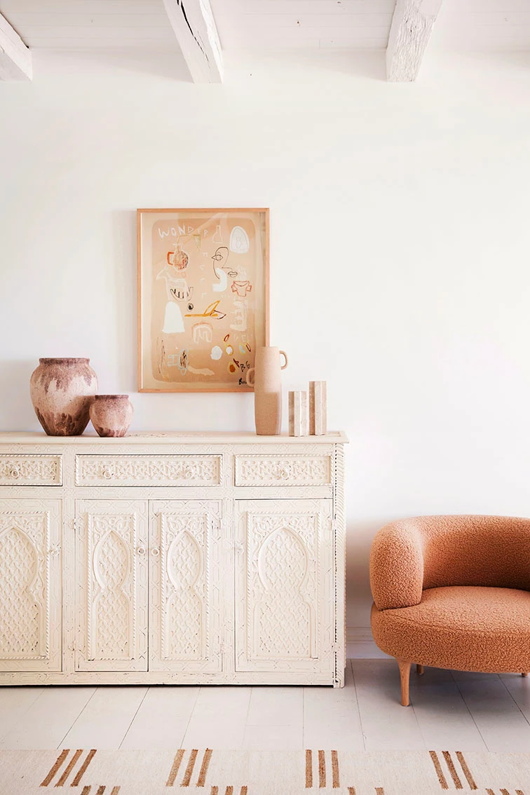 Neutral buffet in living room with brown armchair and decor