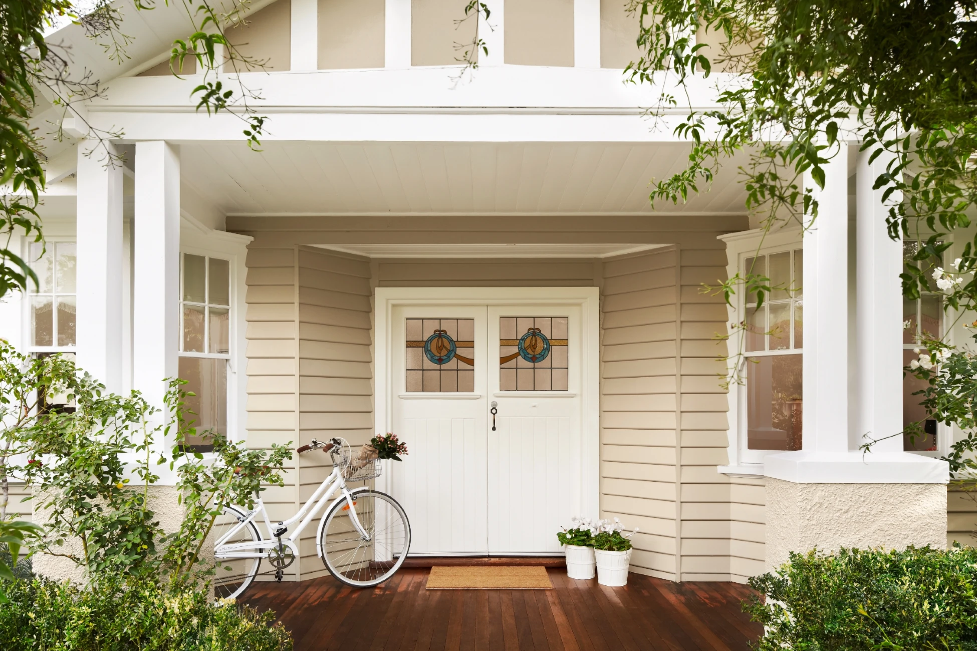 Neutral weatherboard house, white double doors with stained glass inset, white trim.