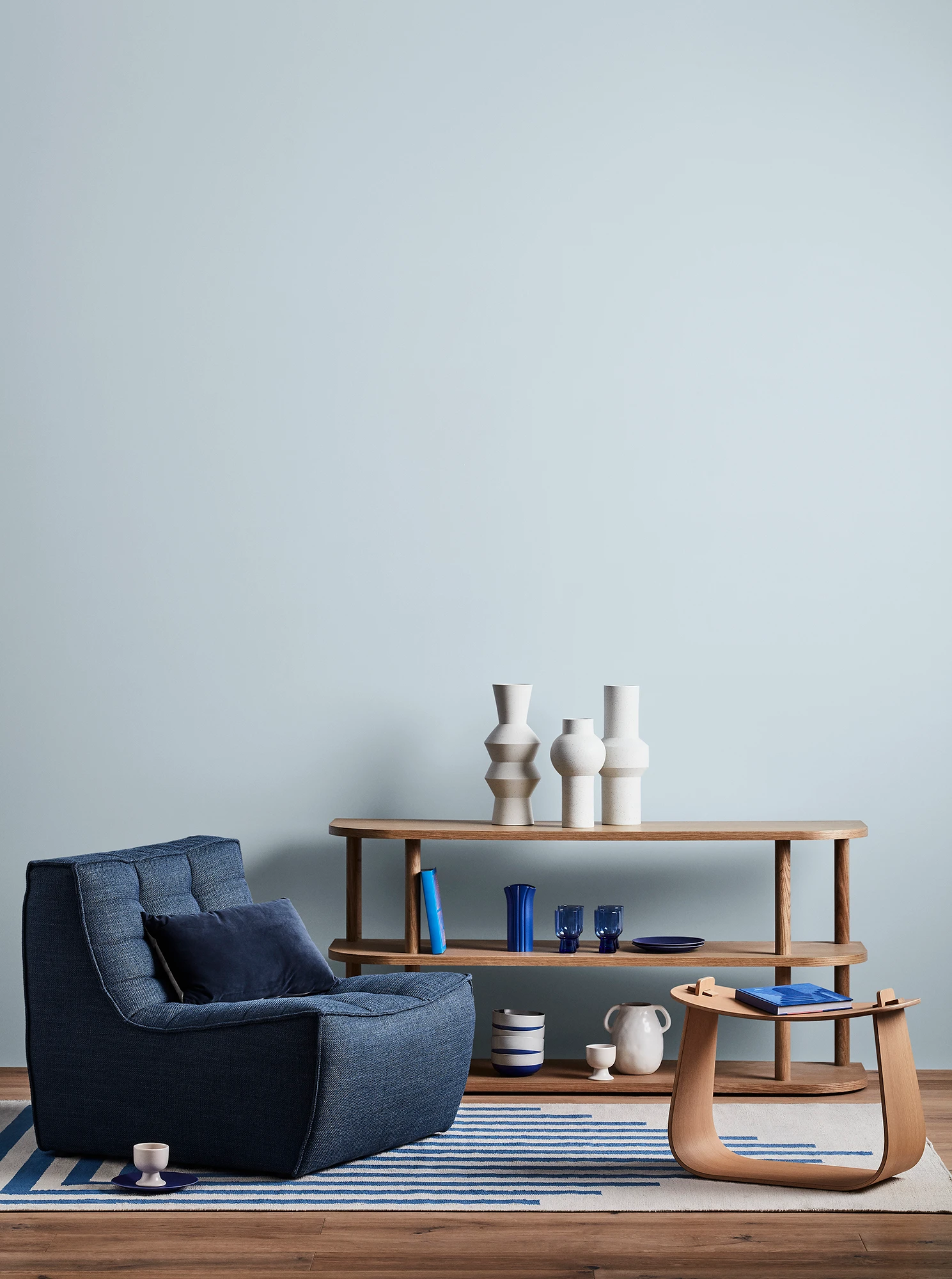 Blue living room with blue armchair, wooden coffee table and shelves with blue and white decor.