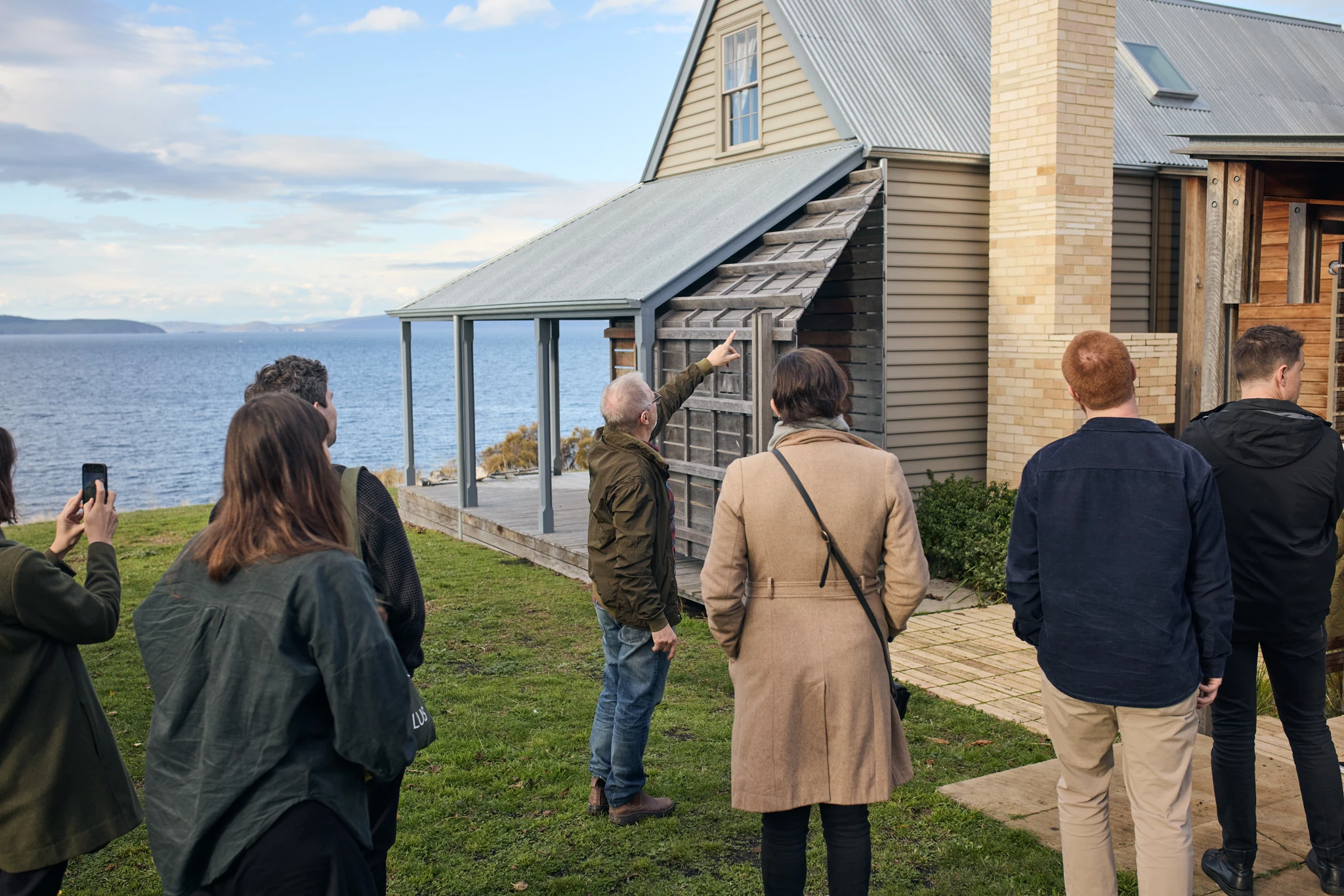 Adults looking at weatherboard cottage overlooking ocean.